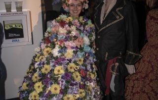 A woman in a vibrant floral dress poses with a man in a pirate costume at the Halloween event in Denver.