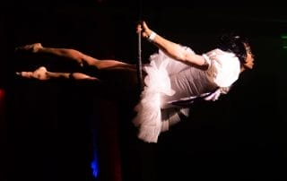 Aerial performer in a white dress gracefully swinging above the crowd at the Halloween event in Denver.