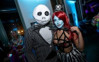Couple in Halloween costumes inspired by classic characters, posing together at a lively Denver Halloween event.