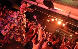 A performer in a vibrant floral costume captivates the audience at a Halloween event in Denver.