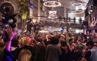 Crowd enjoying the festivities at Paranormal Palace, with colorful costumes and decorations filling the space.