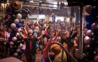 Crowd dancing at Paranormal Palace, surrounded by colorful balloon decorations and a lively party atmosphere.